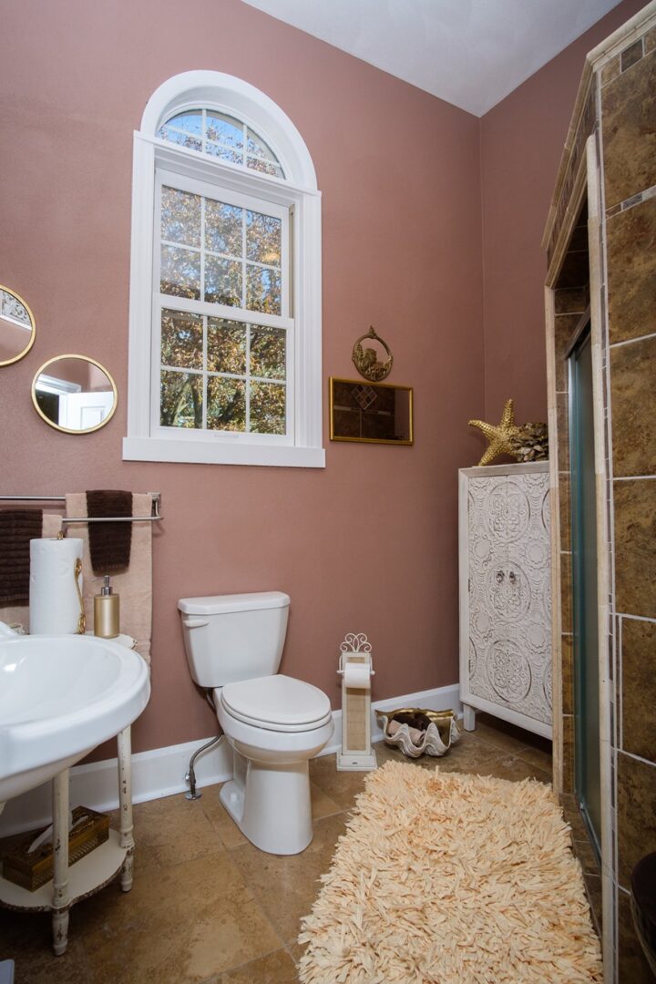 A bathroom with pink walls and white fixtures.