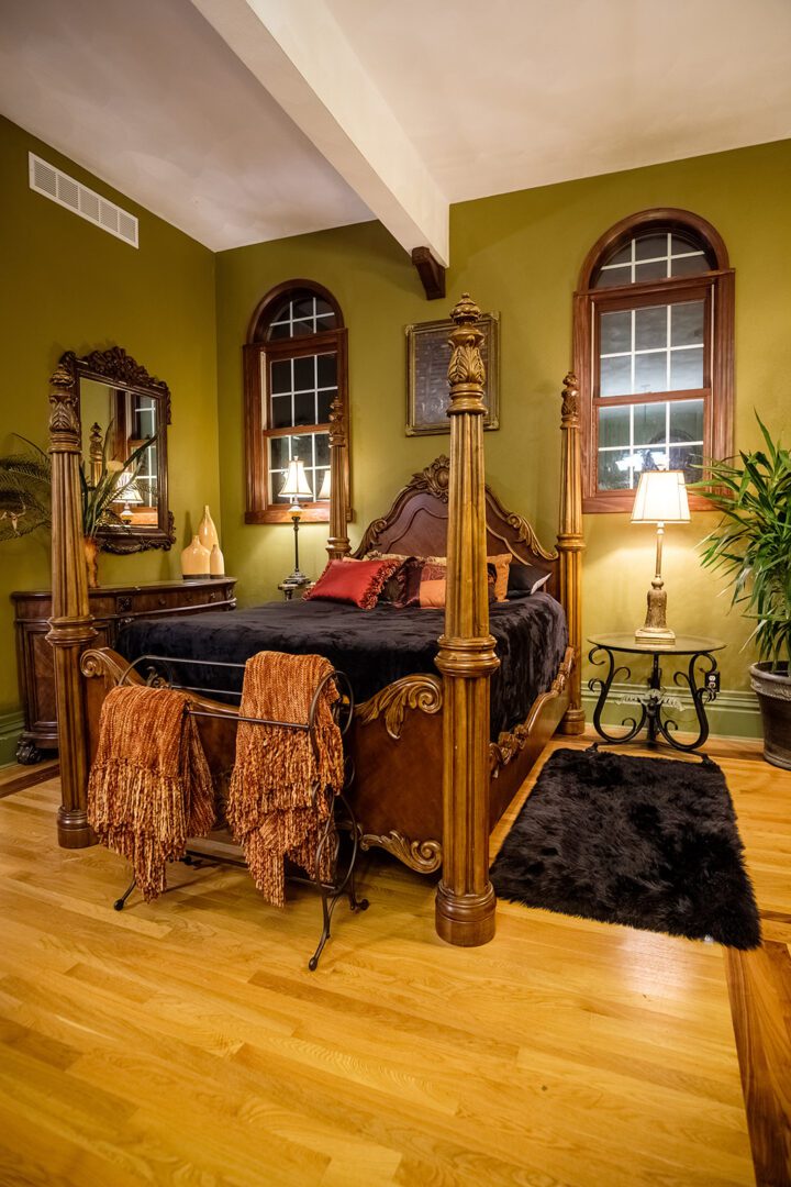 A bedroom with four poster bed and wooden floors.