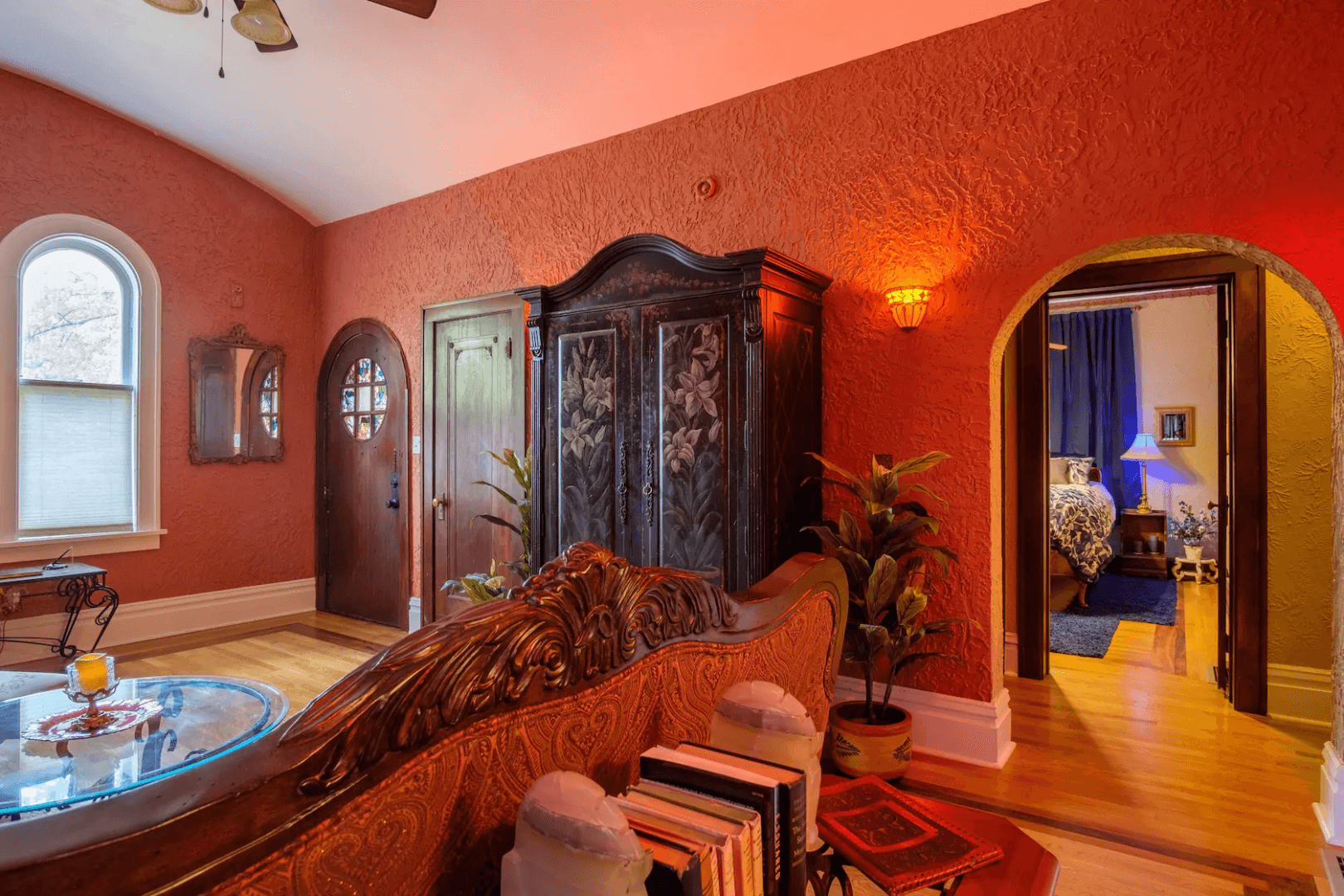 A living room with red walls and a large armoire.