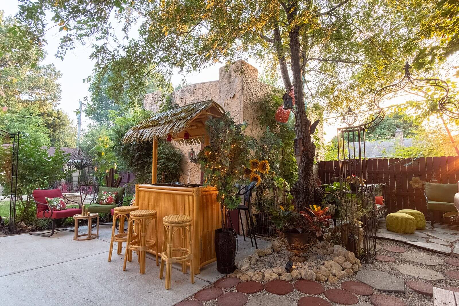 A tiki bar with chairs and tables in the back yard.